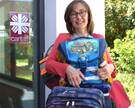 Maria Weiss von der Caritas hält und zeigt mehrere gespendete Schulranzen und Schultaschen.